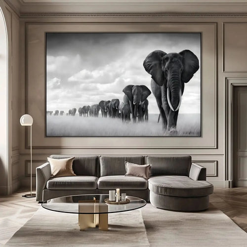 Tableau noir et blanc d'une file d'éléphants avançant dans la savane sous un ciel nuageux, symbole de force et d'unité.