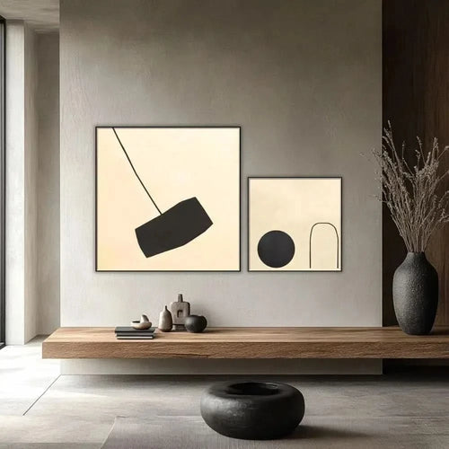 Tableau minimaliste avec fond beige et forme noire suspendue. Contraste subtil, idéal pour un salon moderne.