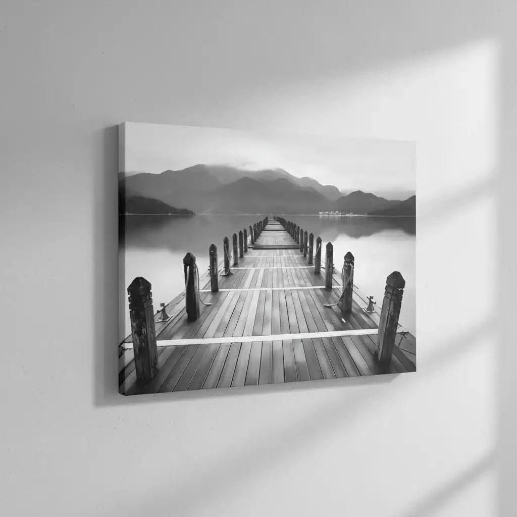 Pont en bois noir et blanc s'étendant vers l'horizon, entouré de montagnes, créant une ambiance sereine et contemplative.