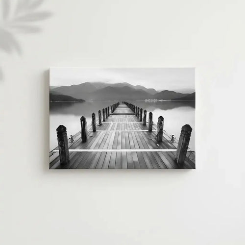 Pont en bois noir et blanc s'étendant vers l'horizon, entouré de montagnes, créant une ambiance sereine et contemplative.