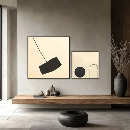 Tableau minimaliste avec fond beige et forme noire suspendue. Contraste subtil, idéal pour un salon moderne.