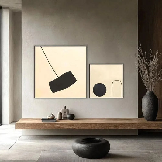 Tableau minimaliste avec fond beige et forme noire suspendue. Contraste subtil, idéal pour un salon moderne.